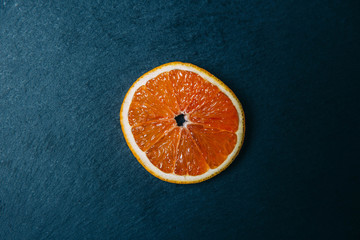 Halved/Sliced Orange Photographed on a Dark Stone. The orange is the fruit of the citrus species Citrus × sinensis in the family Rutaceae. 