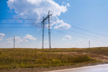 High voltage lines in agricultural landscape on a sunny day with white clouds in the blue sky