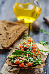 Red fish, arugula and sesame sandwich on a dark wooden background