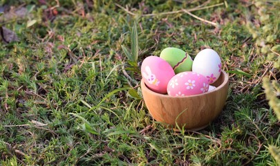 colorful Easter eggs in wood bowl on sack and rustic wood background