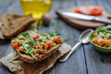 Red fish, arugula and sesame sandwich on a dark wooden background