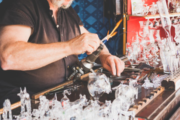 Hands of the handicraftsman making a glass subject at fair of crafts.