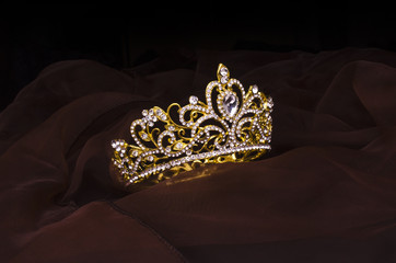 gold crown with diamonds isolated on the fabric © vitaly tiagunov