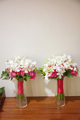 Couple of red rose and white flower bouquet decorating with red pink ribbon on the glass vase