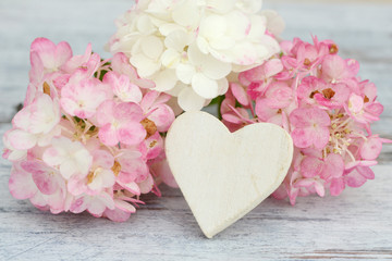 White heart and flowers lying on wood