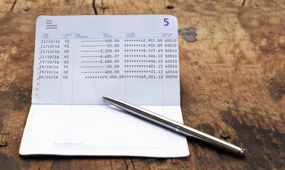 bank account book with silver luxury pen on rustic wood background with copy space