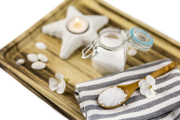 Aromatic sea bath salt on wooden spoon on wooden tray, ocean theme, minimal set spa salon concept, isolated on white.