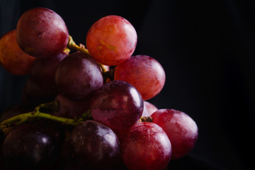 closu up red grapes in a white bowl in the dark corner