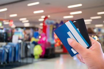 Female hand holding and showing two credit cards for payment shopping with  department store blurred background. e commerce concept.