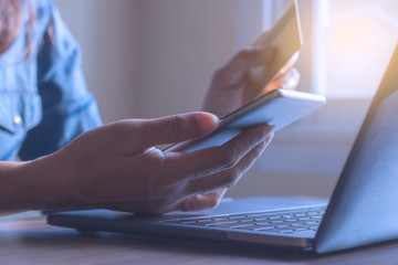 Businesswoman hand using mobile smartphone and  credit card for online shopping and payment, work on laptop computer at home office.  m banking concept.
