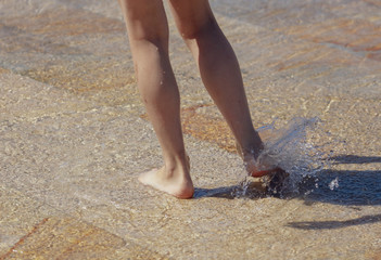 The legs of a girl in the water in a fountain