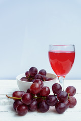 Grape and glass of wine on a white wooden floor