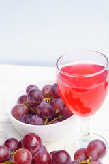 Grape and glass of wine on a white wooden floor