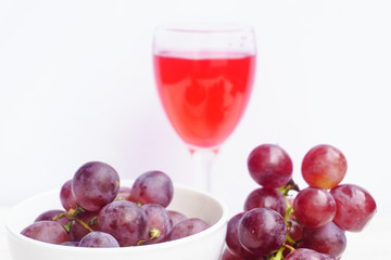 Grape and glass of wine on a white wooden floor