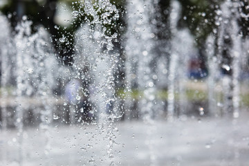Splashing water from a fountain in the park as a background