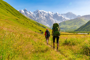 Young active girls hiking in Greater Caucasus mountains, Mestia district, Svaneti, Georgia - obrazy, fototapety, plakaty