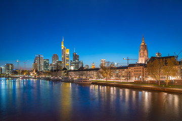 Fototapeta premium View of Frankfurt am Main skyline at dusk along Main river with cruise ship in Frankfurt, Germany