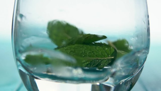 Mint leaves dropping into cocktail glass