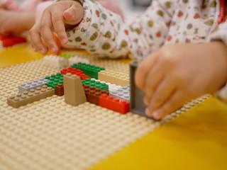 Hands of a baby playing colorful interlocking plastic bricks - child development through playing toys