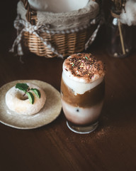 Chocolate Milk Shake with Coffee and Colorful Sugar Sprinkles As Topping and Blur doughnut and Mint Leaf on Wooden Table in Cafe