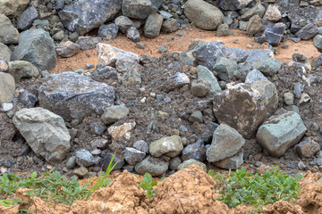 Pile of large granite stones near the grass.