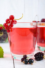 Refreshing drink compote of summer berries in glasses on a white wooden background.