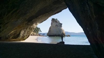 Poster Young woman standing below Cathedral Cove in Coromandel, New Zealand © Michaela