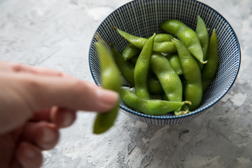 Frau isst Portion grüne, japanische Edamame Sojabohnen in Porzellan Schale
