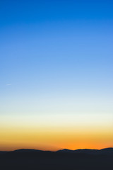 Fototapeta premium Sunset or sunrise background wallpaper photo of blue, orange and yellow sky over a horizont.