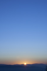 Sunset or sunrise background wallpaper photo of blue, orange and yellow sky over a horizont.
