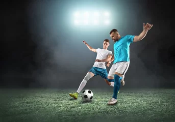 Poster Soccer player on a football field in dynamic action at summer day © Andrii IURLOV