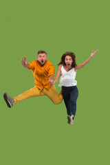 Freedom in moving. Pretty young couple jumping against green background
