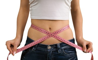 Female fitness model holding a tape measurer around her waist -