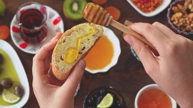 Female hands spreading honey over the bread