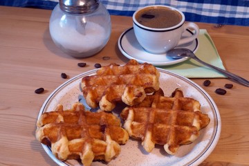 Belgian waffles, cup of coffee, small spoon and glass sugar dispenser