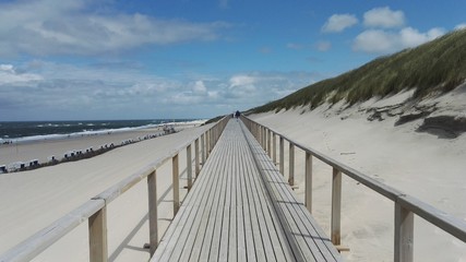 Beautiful photo of wooden promenade at the Sylt seaside between the northern sea and the dunes