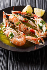 Gourmet seafood scampi or langoustine or Norway lobster are served on a black plate with sauce and lemon. vertical