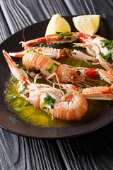Delicious boiled scampi or langoustine or Norway lobster close-up on a plate with sauce and lemon on a table. vertical