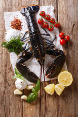 Beautiful seafood uncooked lobster closeup with lemon and herbs on a table. Vertical top view
