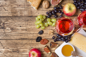Cheese, wine, baguette grapes figs honey and snacks on the rustic wooden table top with copy space.