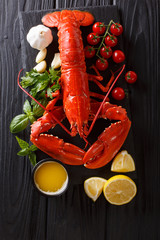 Expensive organic food: boiled lobster with lemon, garlic, fresh tomatoes and herbs close-up on a table. Vertical top view