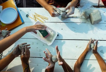 Children's hands crumble pieces of clay
