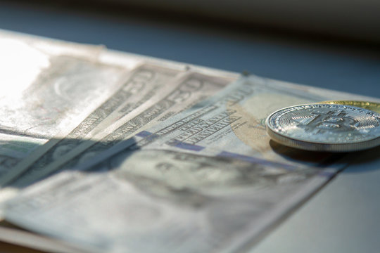 Coins bitkoin lie on dollar bills in the rays of the setting sun. The concept of bitcoin, crypto currency and dollars. Photo of dollars and coins bitcoin with beautiful light.