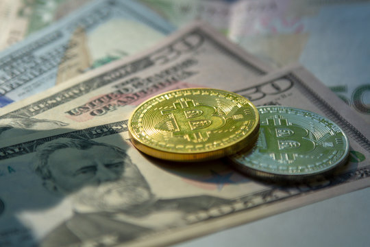 Coins of crypto currency in the background of monetary denominations. The rate of the currency in relation to the dollar. An image of a crypto-currency with dollar cashes.