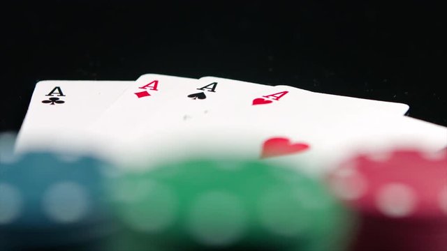 Poker winning chips and four aces on the black background