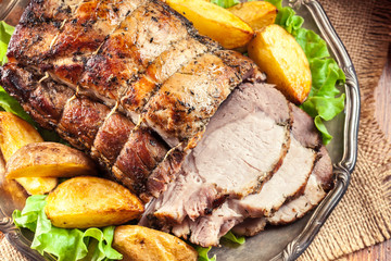 Roasted pork loin with baked potatoes and herbs