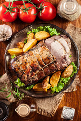 Roasted pork loin with baked potatoes and herbs
