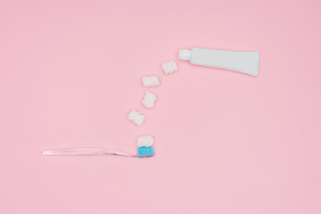 Obraz na płótnie Canvas top view of marshmallows, toothbrush and toothpaste tube isolated on pink