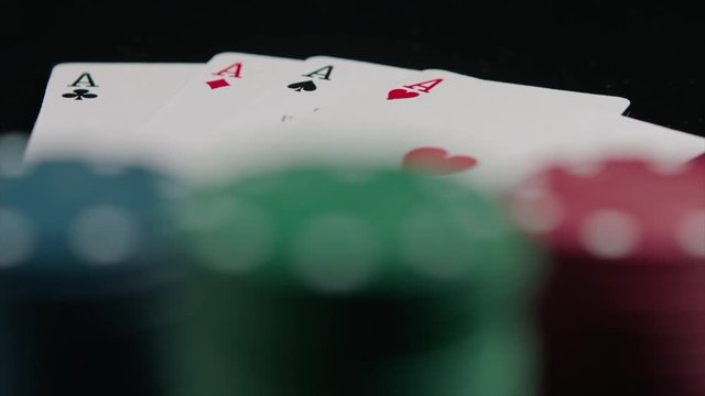Poker chips and four aces on the black background