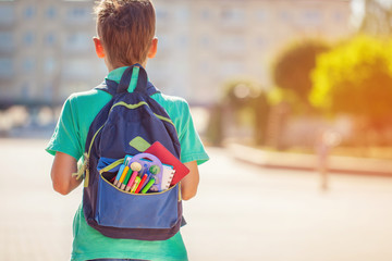 Back to school concept. Schoolboy with full backpack go to school. Back view